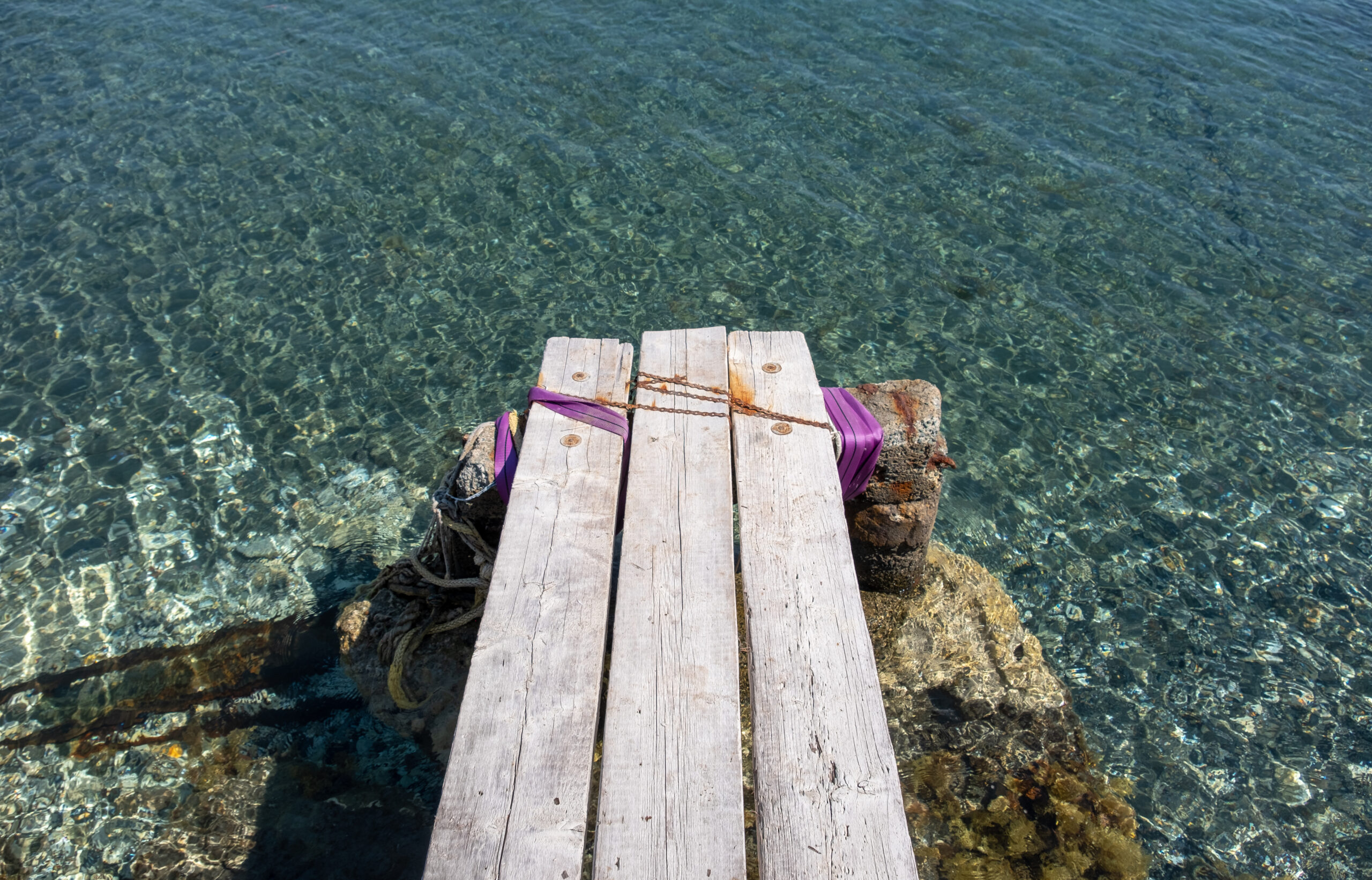 A small wooden pier over clear water at Governor's Beach near Limassol, Cyprus